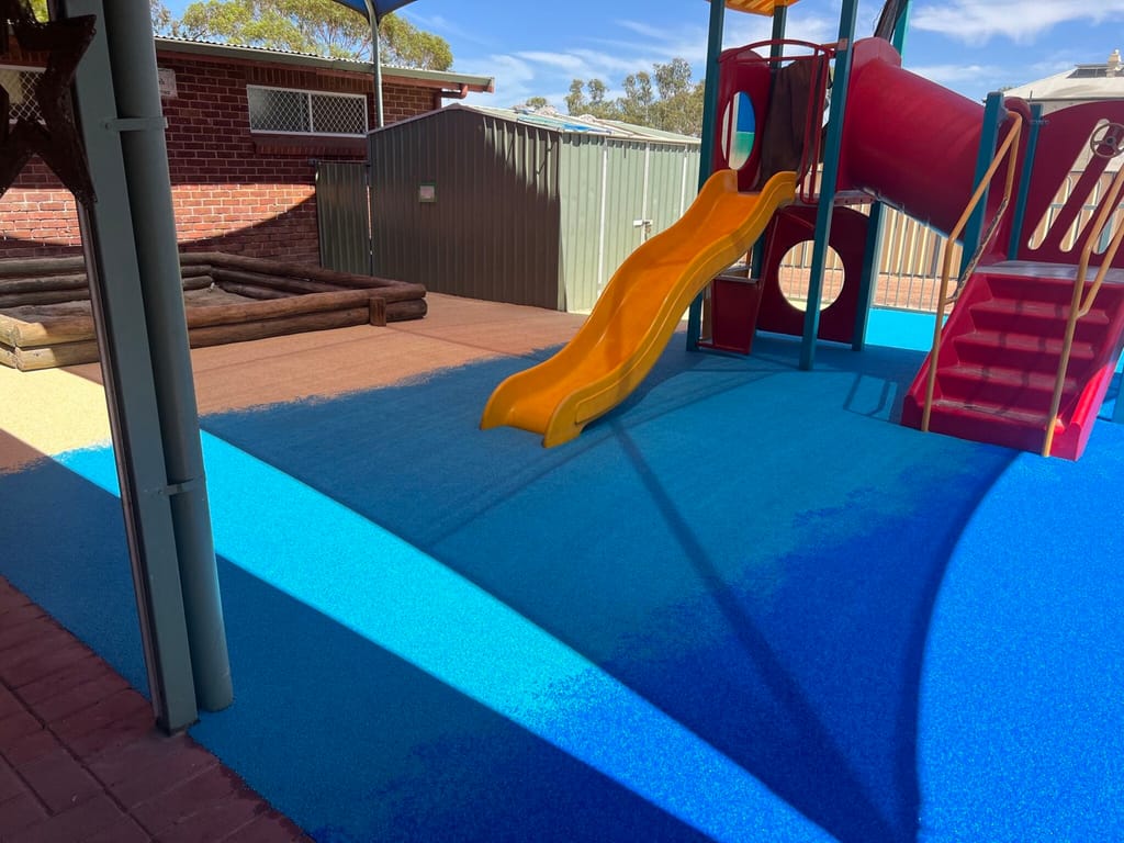 Small neighbourhood toddler playground with wet-pour safety surfacing and light, distributed use