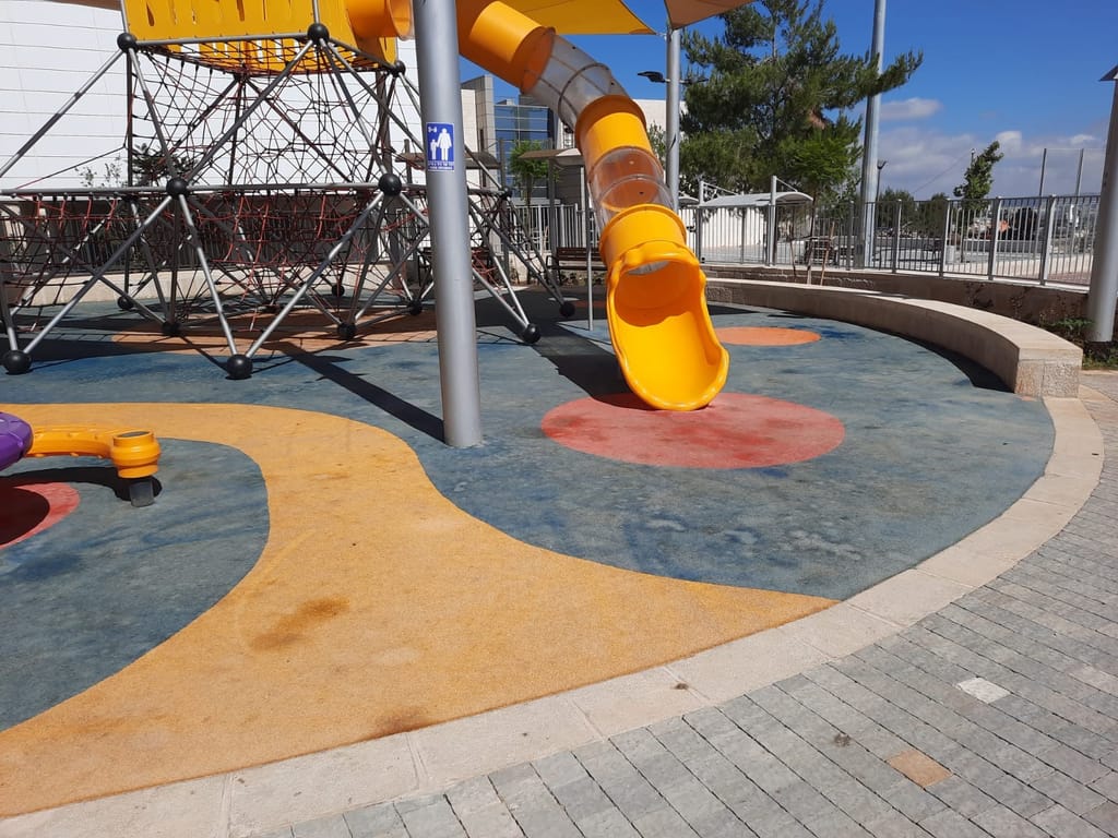 A faded EPDM playground surface where the original design is barely visible